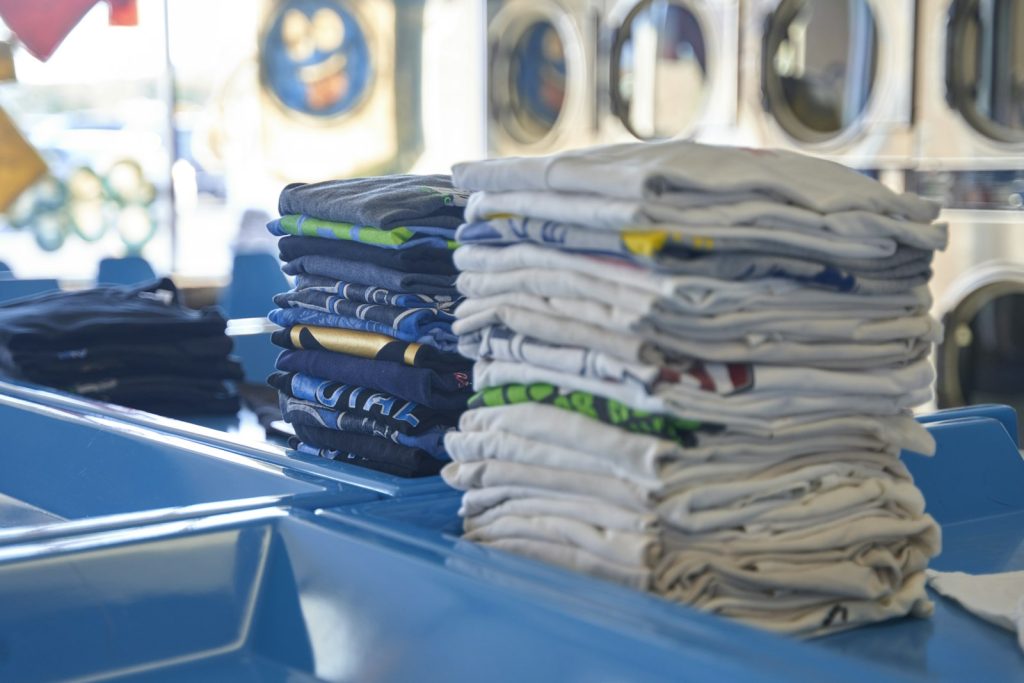 Stack of neatly folded shirts ready for customer pickup at a laundry shop