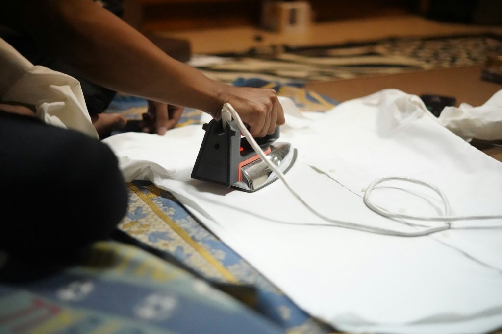 Laundry staff ironing a white shirt as an add-on service